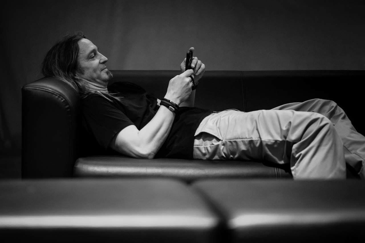 Ich, Marc Thiele, liege grinsend auf einer Couch und schaue auf das Mobiltelefon.