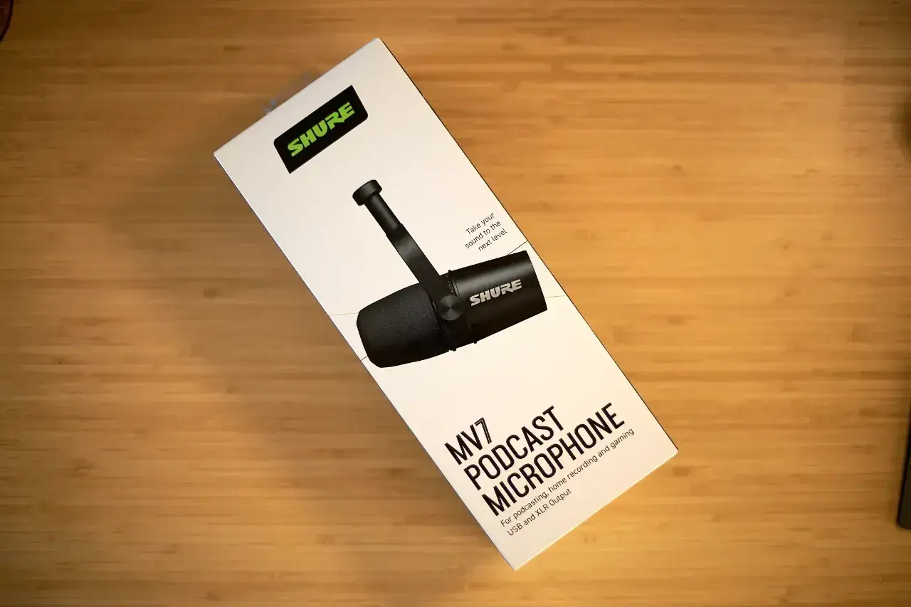 Ein Foto von der Verpackung des Shure MV7, die weiß ist und das schwarze Mikrofon von der Seite zeigt